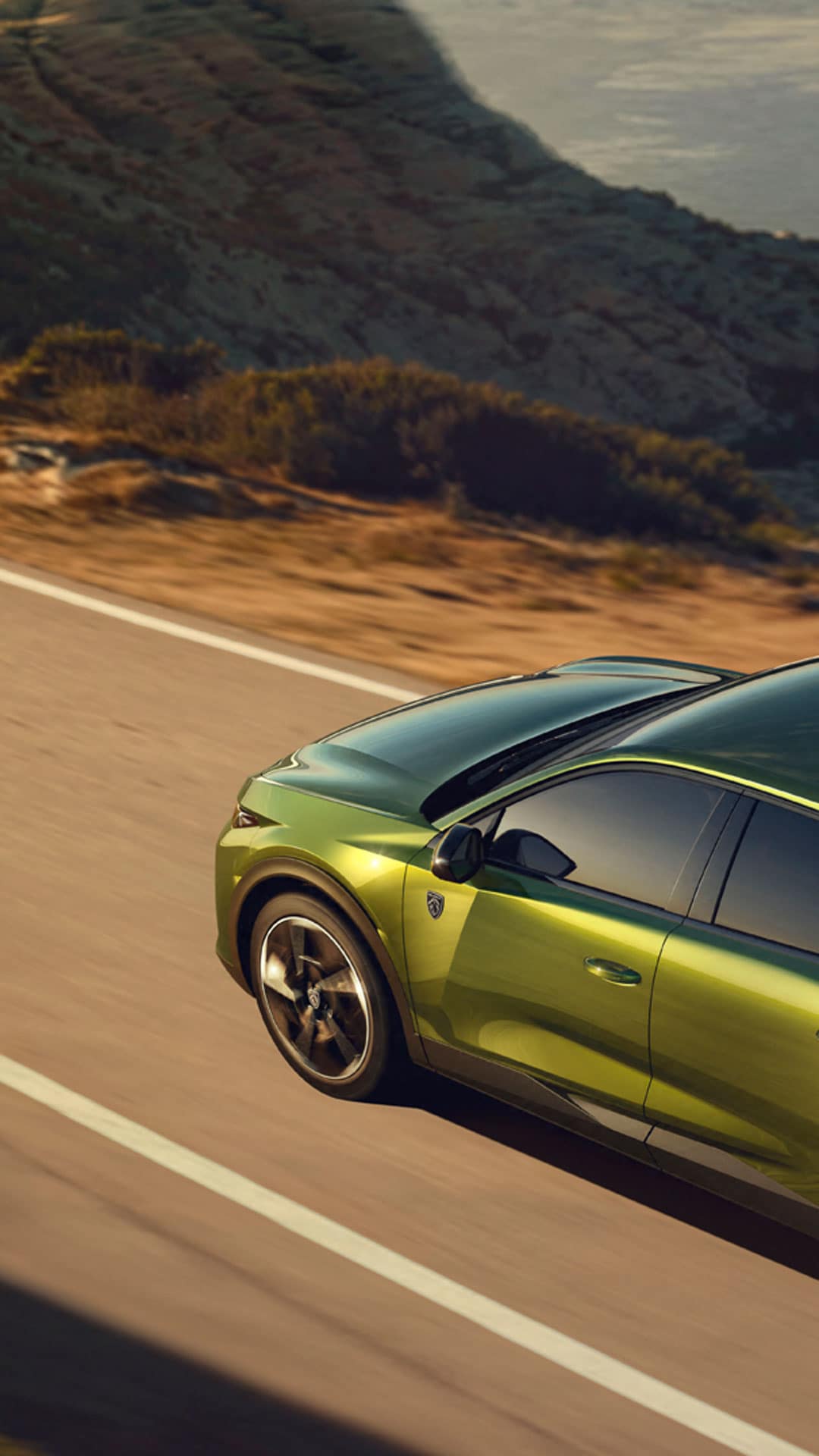 Der neue PEUGEOT E-408 auf einer Straße am Meer