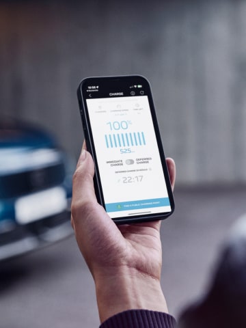 Woman with smartphone in front of the PEUGEOT E-3008 Dual Motor